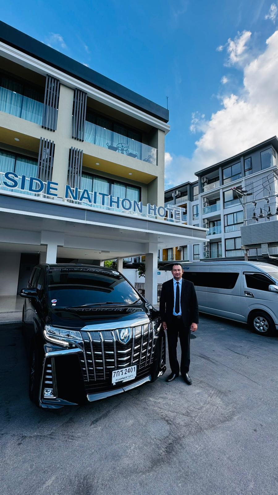 คนขับมืออาชีพในชุดสูทยืนข้างรถ Toyota Alphard สีดำ บริการรับส่งระดับพรีเมียมในภูเก็ต
